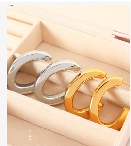 Close-up of gold and silver C-shaped hoop earrings in a velvet jewelry box