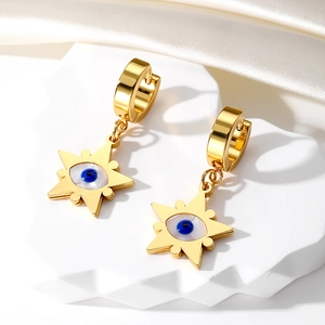 Detail of gold evil eye star earrings on white stone display with silk background