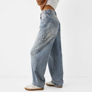 Gros plan d'un jean cargo taille haute à jambes larges avec poches cargo et délavage stone