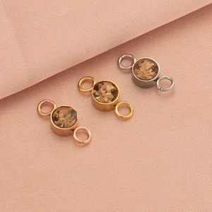 Three-color stainless steel birthstone connectors with round crystals on pink fabric