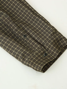 Detailaufnahme des braunen karierten Hemdärmels mit schwarzen Druckknöpfen und Flanell