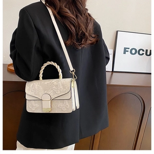 Détail du sac à main beige gaufré papillon avec poignée tressée et accents dorés