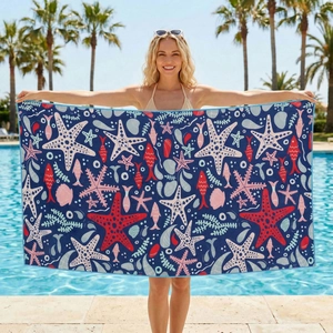 Microfiber beach towel with starfish and marine life patterns shown near an outdoor pool