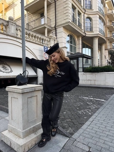 Outdoor street style shot of a black crewneck sweatshirt with Manifest Yourself lettering