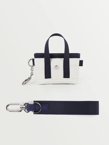 Dettaglio della mini borsa tote in tela color crema con cinturini blu e clip in metallo
