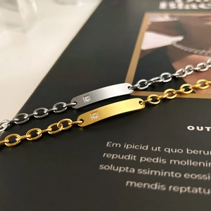 Macro shot of minimalist gold and silver curb chain bracelets with crystal bar pendants