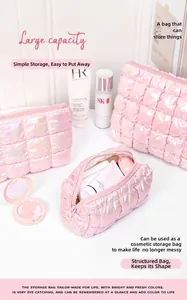 Detail of pink iridescent quilted puffer makeup bag with glossy finish and square grid pattern