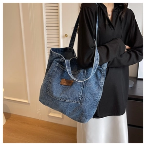 Detailed view of large capacity blue denim tote bag with brown leather patch on front