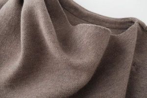 Close-up of premium dark brown knit fabric texture and fine stitching on the scarf coat