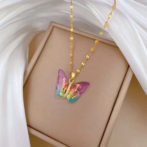 Close-up of golden butterfly pendant with rainbow gradient and glitter on jewelry box