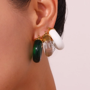 Detail of C-shaped acrylic hoop earrings in green and white with gold-plated base