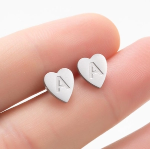 Gros plan détaillé d'une boucle d'oreille cœur en acier avec lettre A gravée en argent