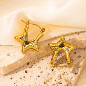 Detailed view of gold star hoop earrings with white zircon on textured stone and silk