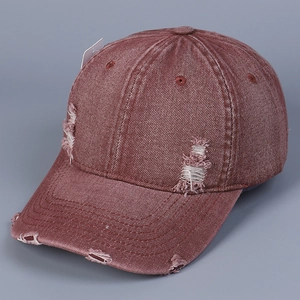 Close-up of vintage washed red denim baseball cap with distressed torn edges and detail
