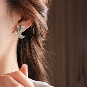 Detail view of light green butterfly tassel earrings with silver base on a female model
