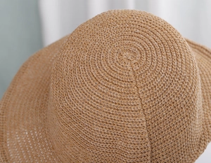 Close-up of spiral woven straw texture on top of khaki bucket sun hat for women