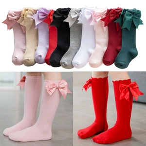 Detail of knee-high baby socks featuring large satin bows and wavy lace cuffs in various colors