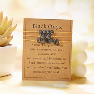 Three-piece black onyx beaded and raw stone bracelet set on descriptive kraft card