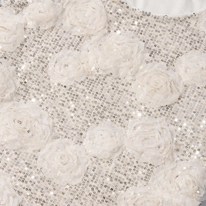 Close-up of 3D mesh flowers and silver sequins on cream-colored fabric embroidery