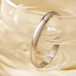 Polished silver titanium steel C-shape open cuff bracelet on elegant beige silk