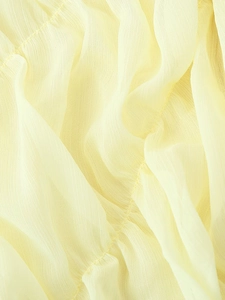 Macro detail of pleated light yellow chiffon fabric showing stitching and texture