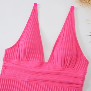 Dettaglio del tessuto a costine rosa e dello scollo a V profondo di un costume da bagno
