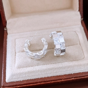Gros plan de boucles d'oreilles C argentées avec zircons carrés en boîte velours