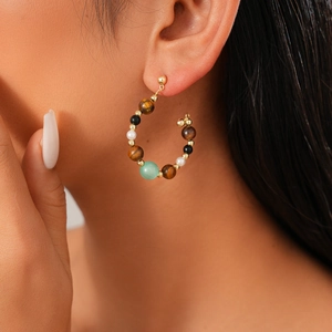 Detail of vintage beaded hoop earrings with tiger eye stone and pearls on model