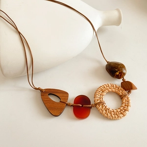 Détail d'un collier vintage avec résine rouge, cercle en rotin et pendentif triangulaire