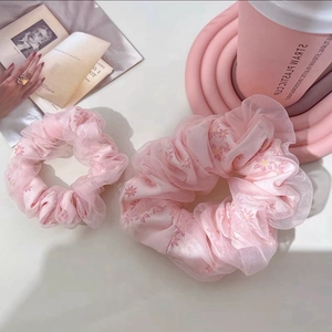 Close-up of pink organza hair scrunchies with delicate floral patterns on a cozy desk