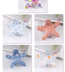 Macro view of blue starfish hair clips with smiley face and floral patterns on white background