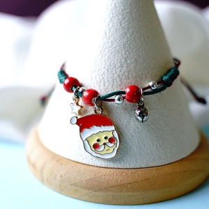 Braided Christmas bracelet with Santa Claus charm and festive beads on a display stand
