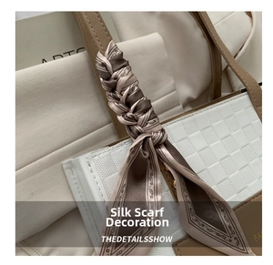 Detail of paisley pattern silk scarf wrapped on a beige leather bag handle