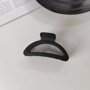 Gros plan d'une pince à cheveux crabe noire mate avec un design incurvé professionnel