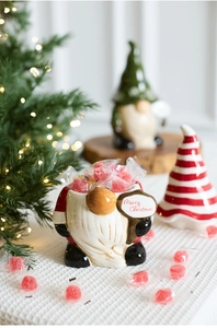 Close-up of ceramic Christmas gnome candy jar with Merry Christmas sign and red sweets