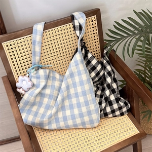 Blue and black checkered canvas tote bags displayed on a vintage rattan chair with plants