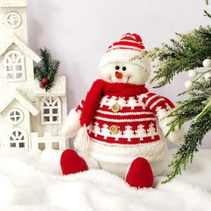 Plush Christmas snowman figurine with red knit scarf and hat in a festive winter scene
