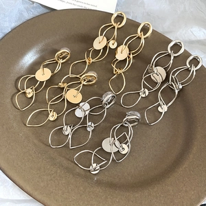 Detailed view of gold and silver layered geometric hollow tassel earrings on a ceramic tray
