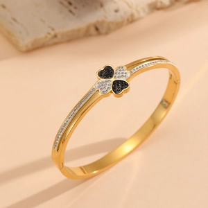 Detailed close-up of gold clover bangle with black and white pavé stones on rock base