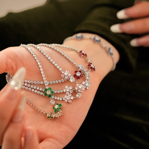 Detail of floral tennis bracelets with colorful zircon stones on deep green background