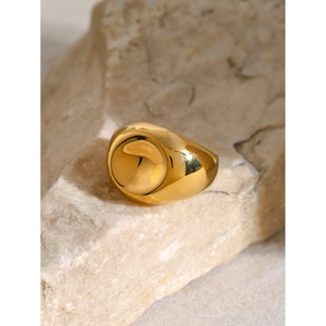 Macro detail of a chunky 18k gold plated spiral ring displayed on a natural stone base