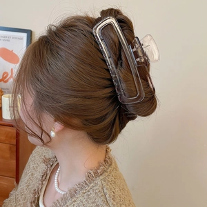 Dettaglio di una grande pinza per capelli in acrilico ambra traslucido per uno stile chignon