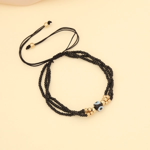 Detailed view of layered black bead bracelet with gold accents and evil eye charm