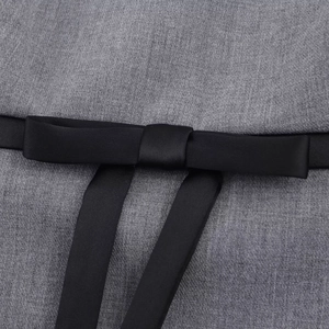 Detailed view of the gray fabric texture with a black satin bow decoration on dress
