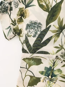 Detailed close-up of a floral summer shirt featuring green leaf patterns and waist drawstrings