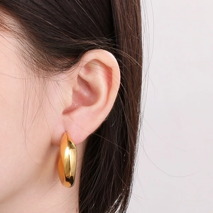 Zijaanzicht van een model met minimalistische 18k vergulde C-vormige holle oorringen
