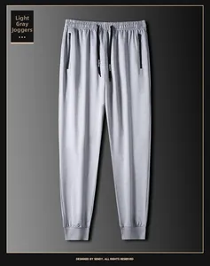 Detalle del pantalón jogger gris claro con cintura elástica, cordón negro y bolsillos con cremallera