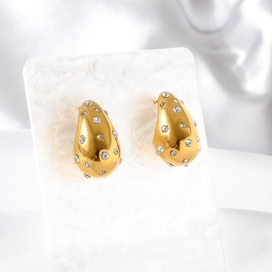 Elegant gold teardrop earrings with white zircon stones on a white marble card