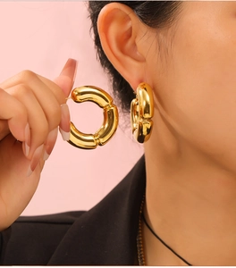 Detailed close-up of chunky gold-plated C-shaped earrings with a hollow bamboo design