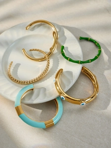 Dettaglio di bracciali in smalto placcati oro 18k con malocchio e texture a bambù
